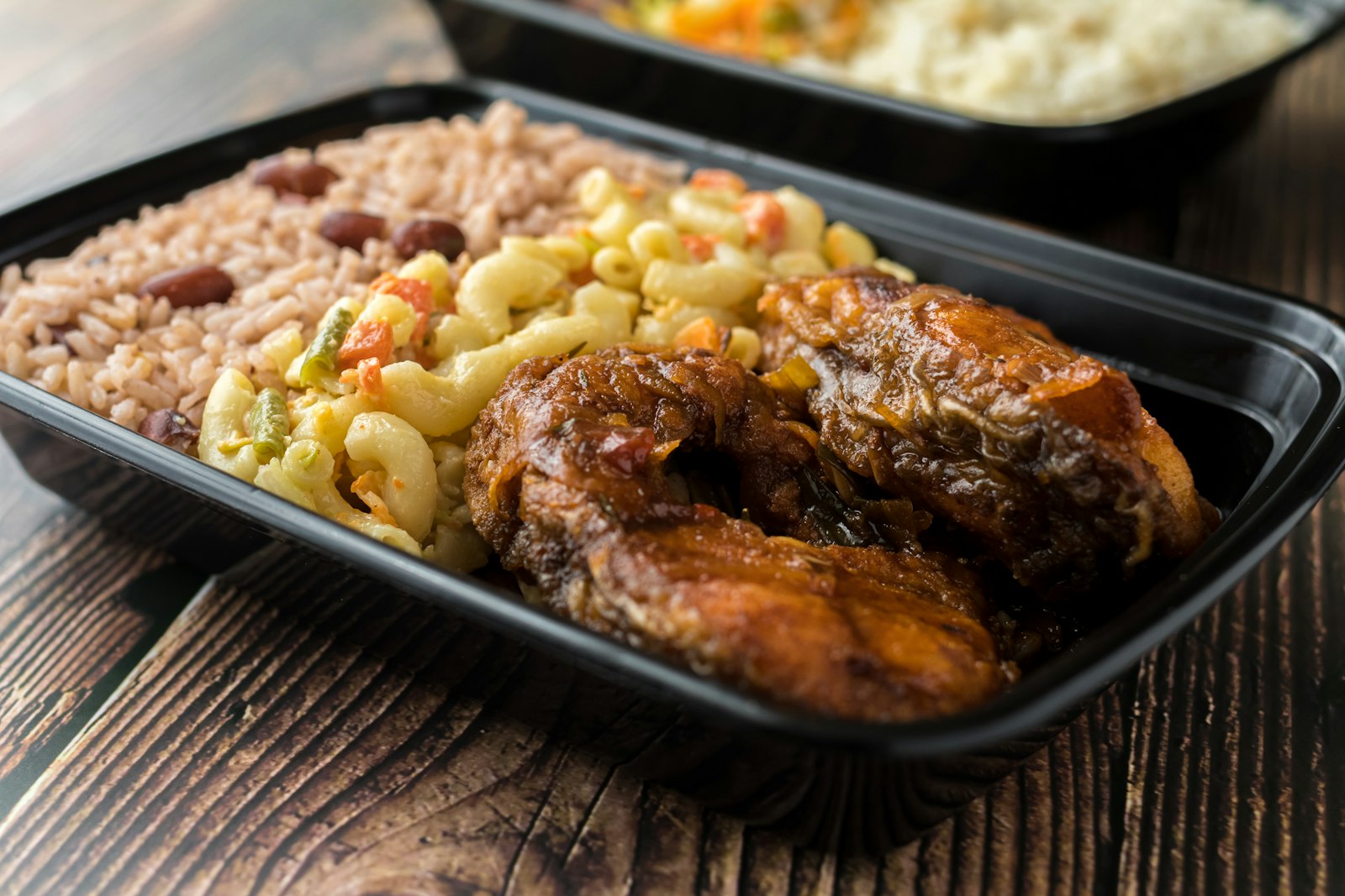 Baked chicken with rice and beans in a takeout tray